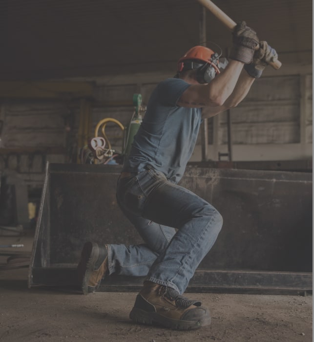 A worker swinging a sledge hammer.