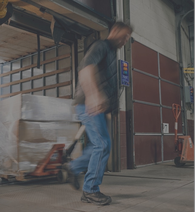 A worker wearing hytest shoes moving with a tool in their hand.